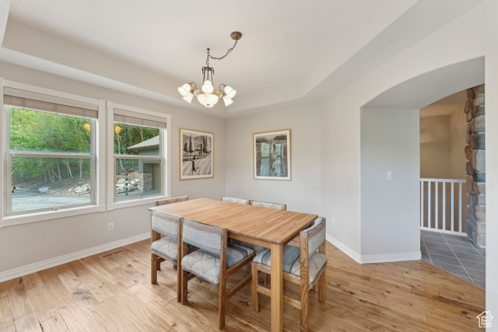 Dining area featuring a chandelier, arched walkways, light wood-style flooring, and baseboards