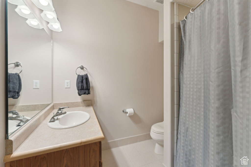 Full bathroom with tile patterned floors, toilet, vanity, baseboards, and a shower with shower curtain