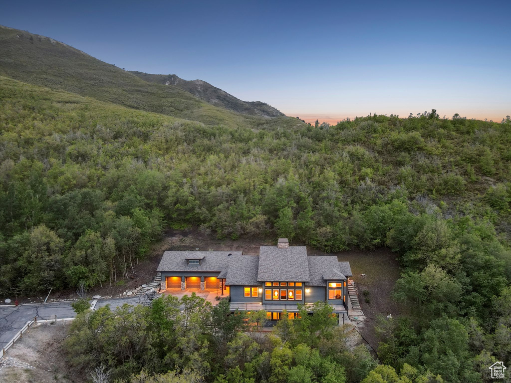 Aerial view of property and surrounding area featuring a forest and a mountain backdrop
