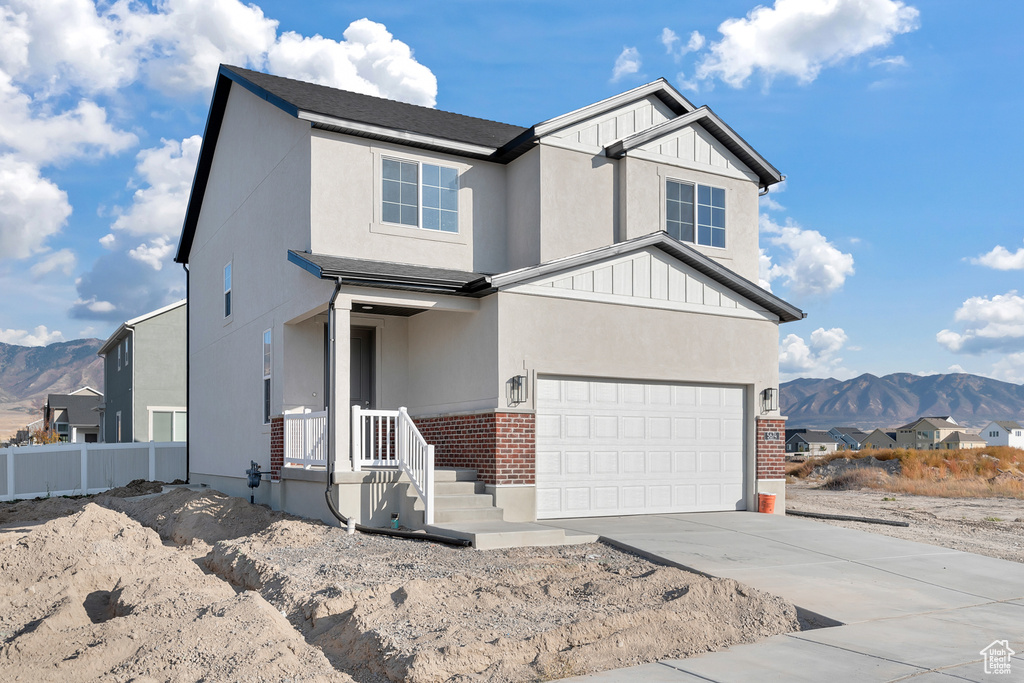 View of front of house featuring an attached garage, a mountain view, fence, concrete driveway, and brick siding