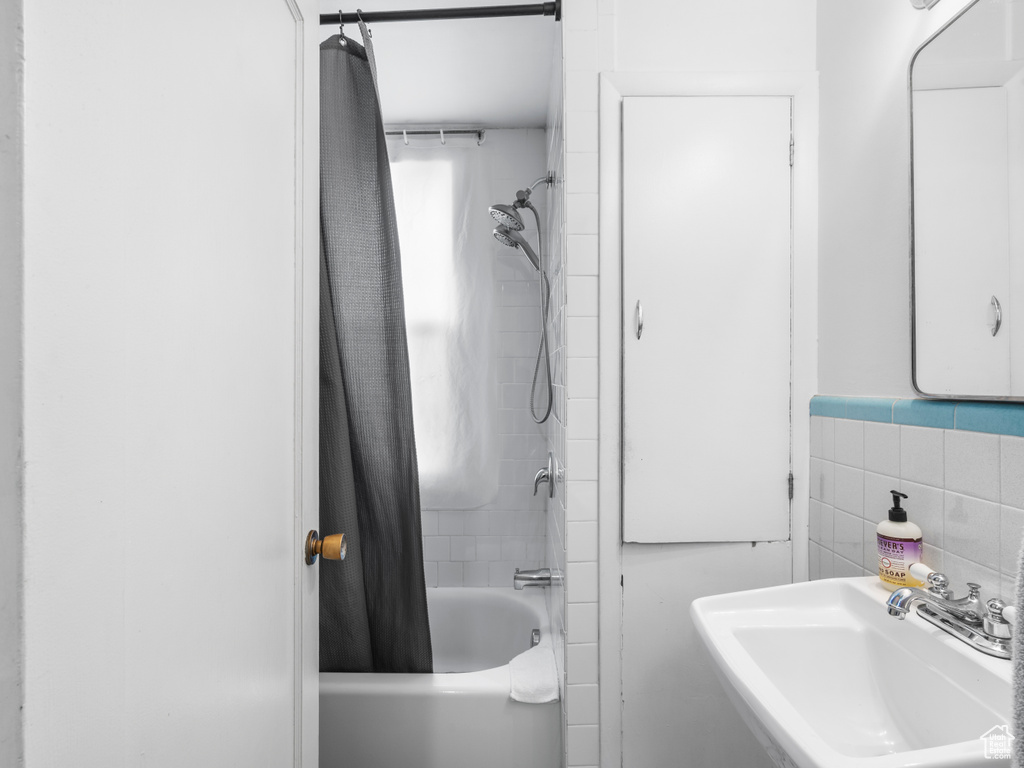 Full bath with a sink, tile walls, and shower / tub combo with curtain