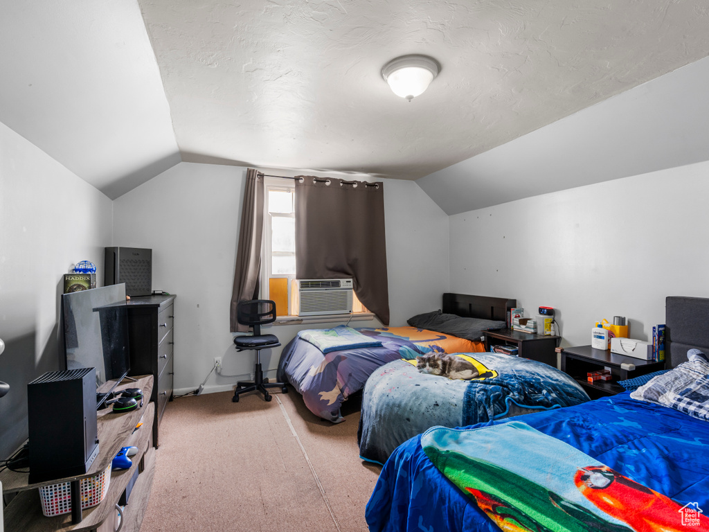 Carpeted bedroom featuring lofted ceiling and cooling unit