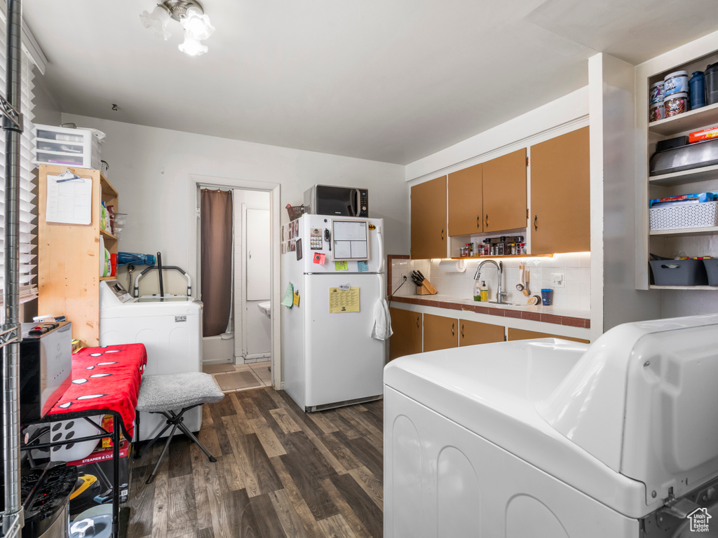 Kitchen featuring freestanding refrigerator, dark wood-type flooring, washer and dryer, tasteful backsplash, and tile counters