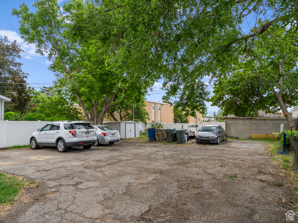 View of parking with fence and a storage unit