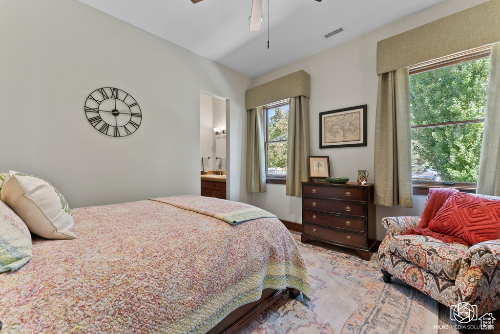 Bedroom with multiple windows, ceiling fan, and connected bathroom