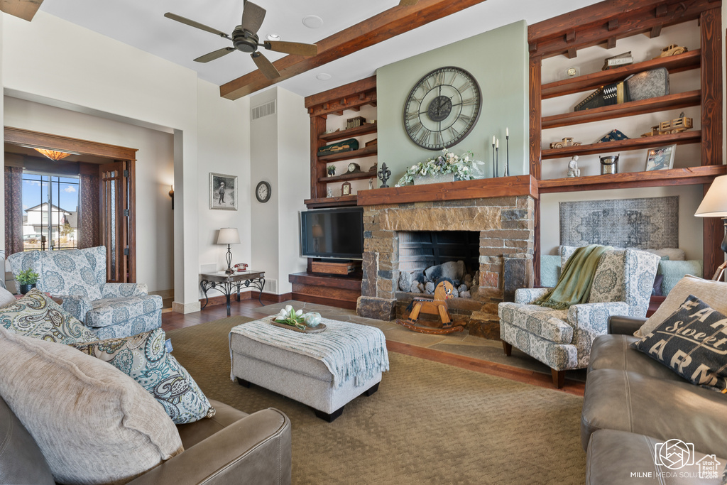 Living area featuring wood finished floors, a fireplace, a ceiling fan, built in features, and baseboards