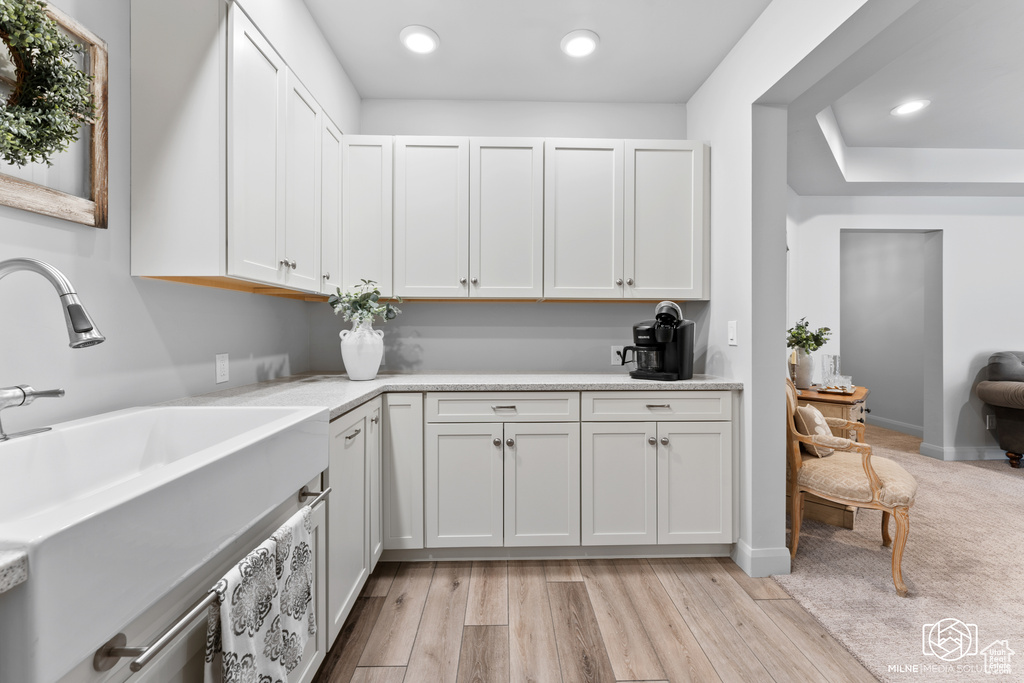 Washroom featuring a sink, recessed lighting, light wood finished floors, and baseboards
