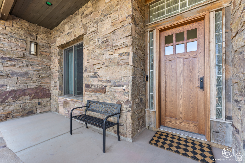 Property entrance with stone siding and covered porch