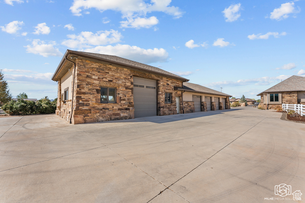 View of building exterior with concrete driveway and an attached garage