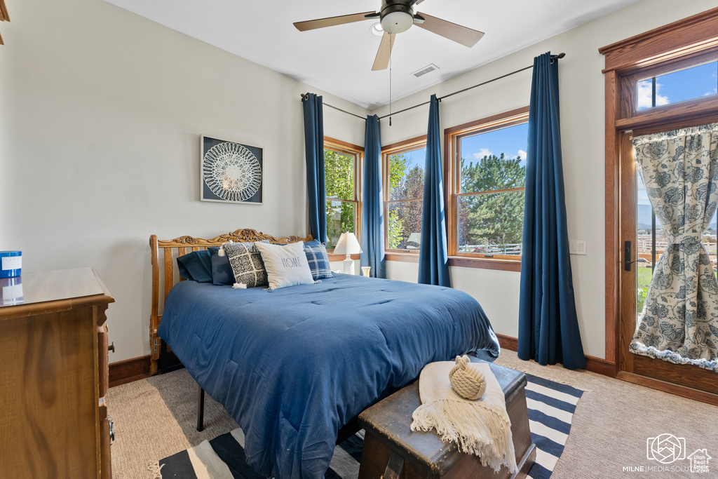 Carpeted bedroom featuring multiple windows, baseboards, and access to exterior