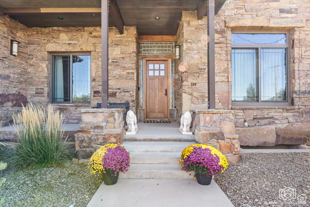 Doorway to property featuring stone siding and a porch