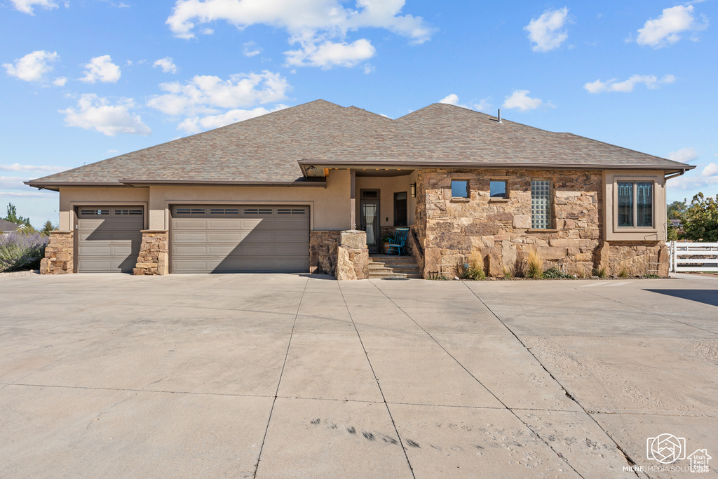 View of front of home featuring stone siding, driveway, an attached garage, stucco siding, and a shingled roof