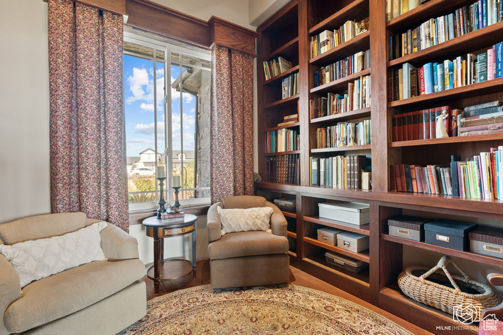 Living area featuring bookshelves, healthy amount of natural light, and wood finished floors