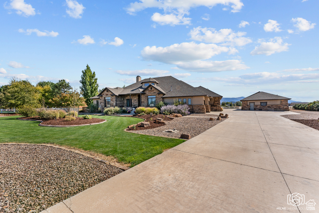 View of front of home featuring curved driveway, stone siding, a front yard, and a chimney