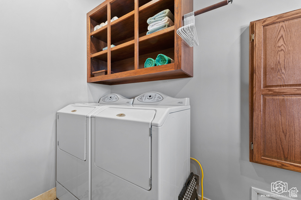 Laundry room with washing machine and dryer, cabinet space, and baseboards