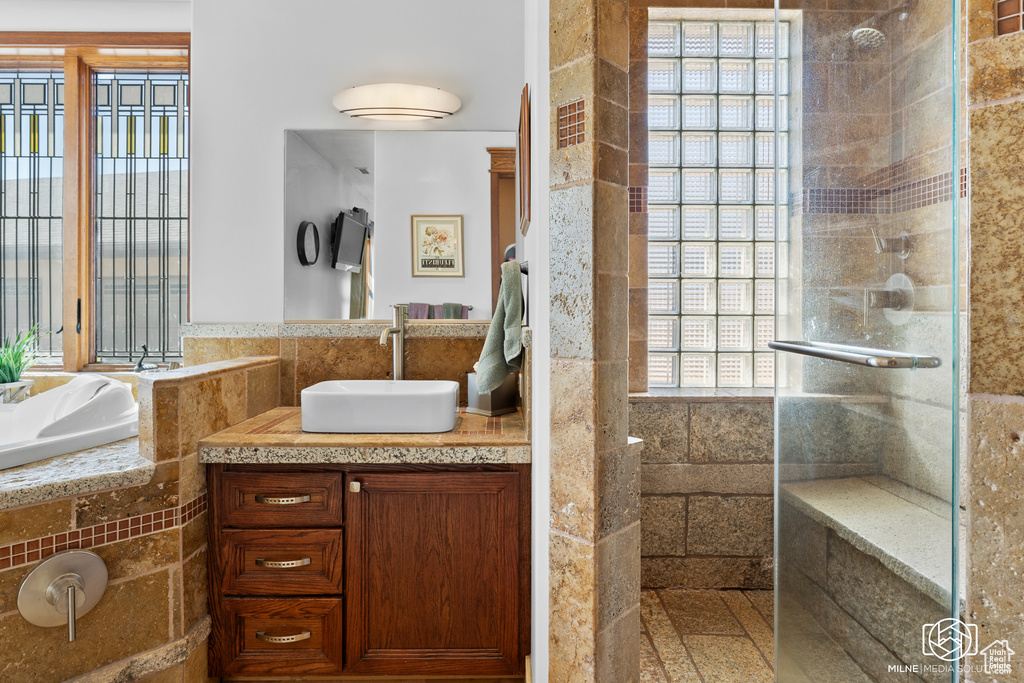 Full bathroom with tiled shower, healthy amount of natural light, vanity, and tile walls