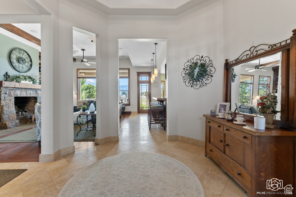 Entryway with ceiling fan, a stone fireplace, light tile patterned floors, a high ceiling, and baseboards