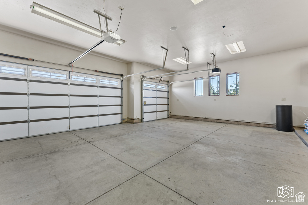Garage featuring a garage door opener and baseboards