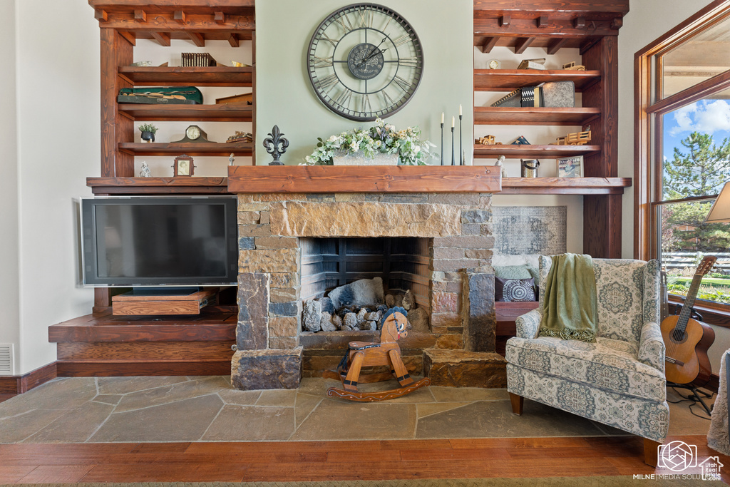Living area with beam ceiling, a fireplace, wood finished floors, baseboards, and built in features