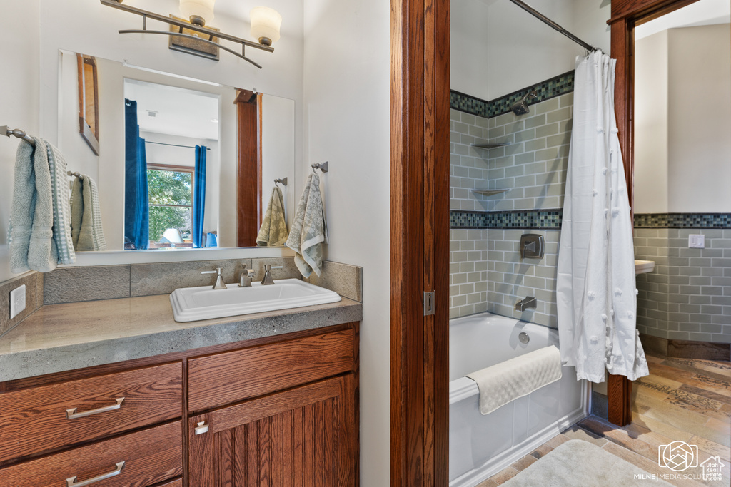 Bathroom featuring shower / bath combo, tile walls, wood finished floors, vanity, and a wainscoted wall