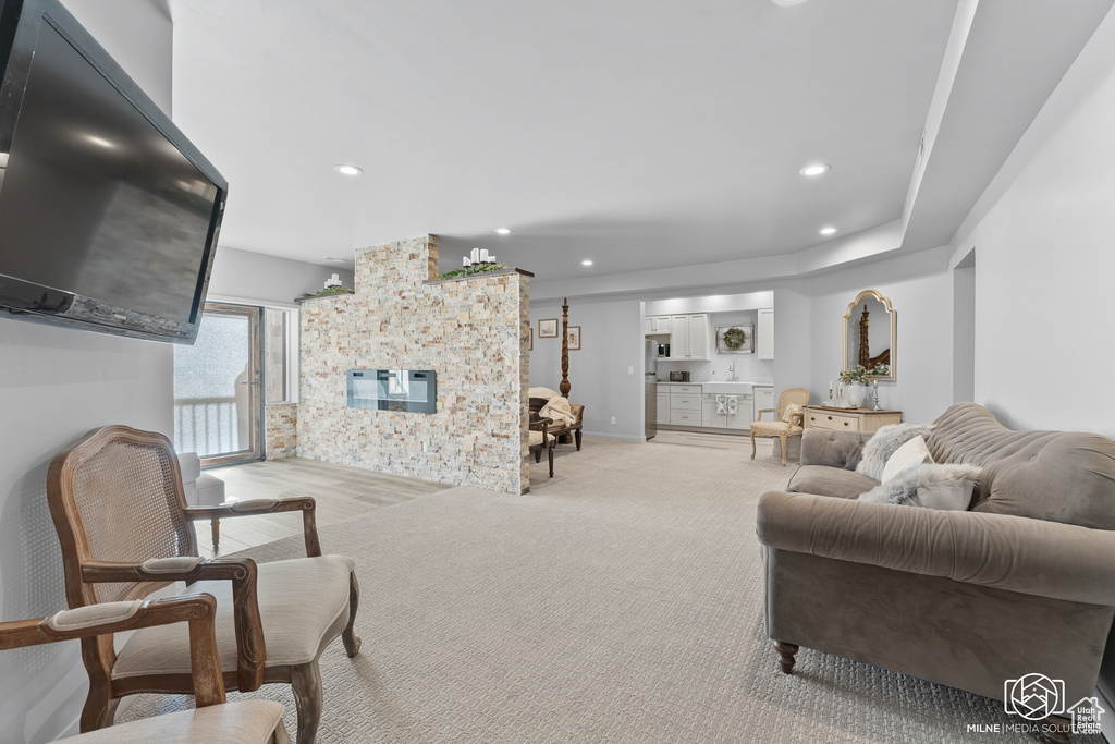 Living area featuring a large fireplace, recessed lighting, light carpet, and baseboards