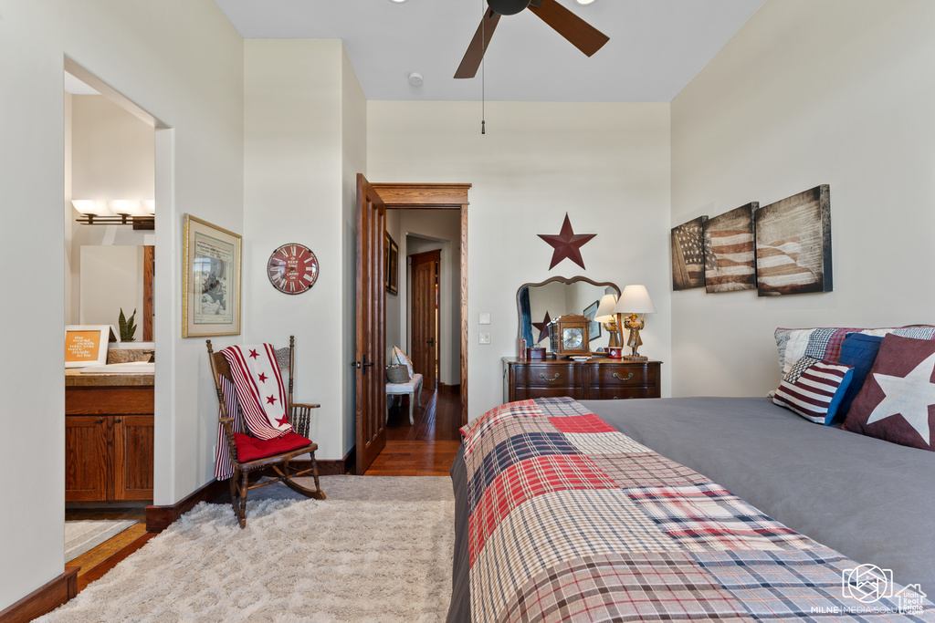 Bedroom with wood finished floors, connected bathroom, a ceiling fan, and baseboards