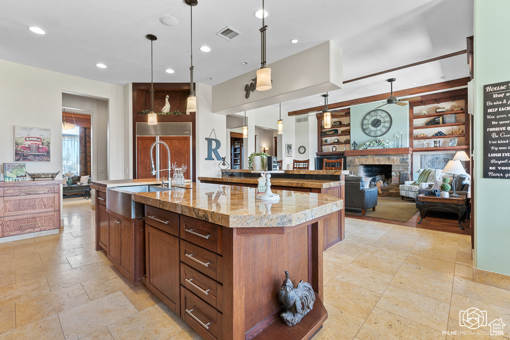 Kitchen with open floor plan, a sink, an island with sink, a fireplace, and recessed lighting