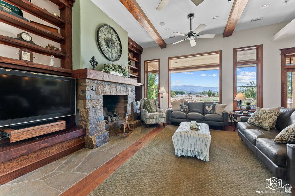 Living area featuring beamed ceiling, hardwood / wood-style flooring, a fireplace, and a ceiling fan