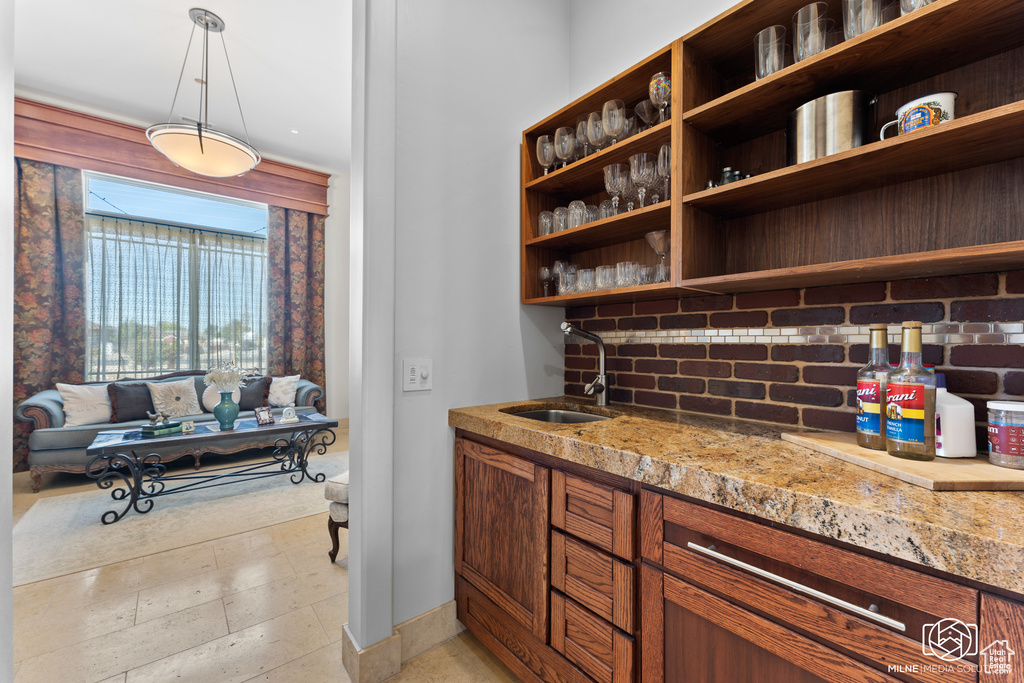 Bar with a sink, decorative backsplash, and pendant lighting
