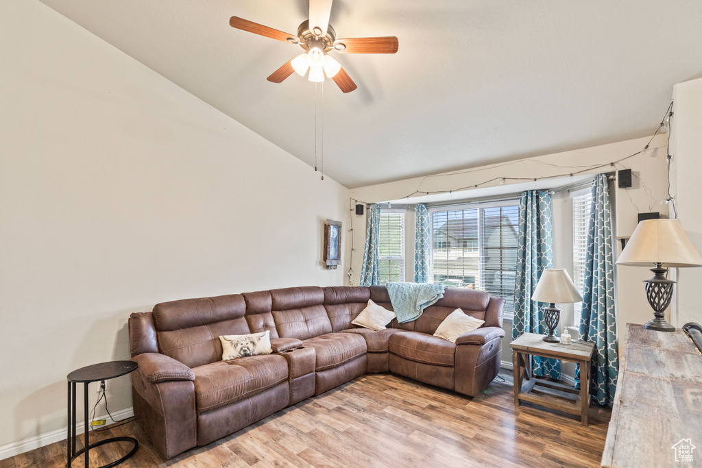Living room featuring lofted ceiling, a ceiling fan, and wood finished floors