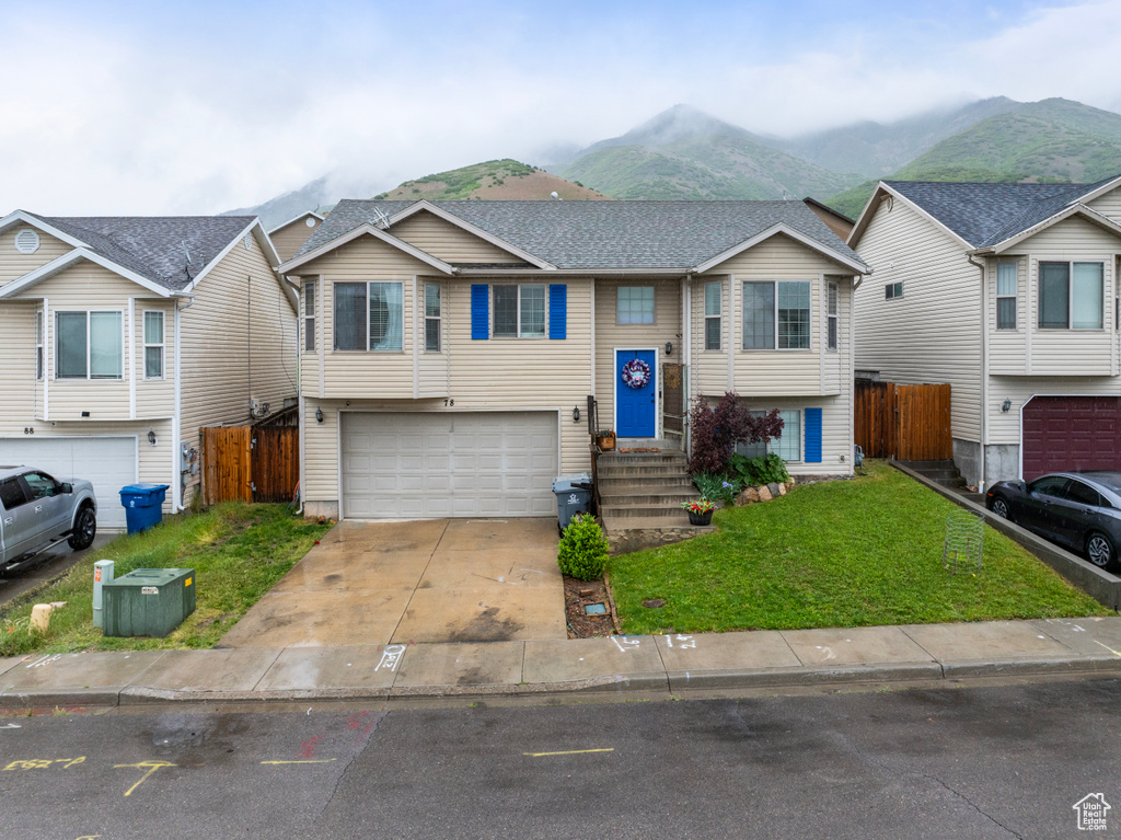 Raised ranch featuring an attached garage, a mountain view, and driveway