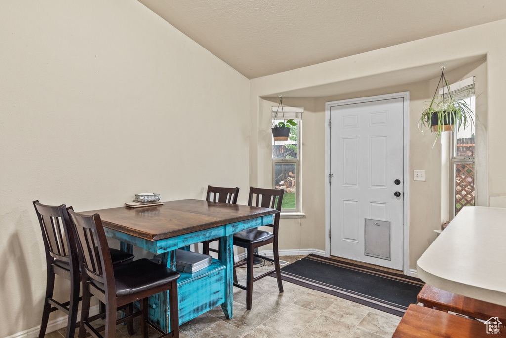 Dining area featuring healthy amount of natural light, vaulted ceiling, and baseboards
