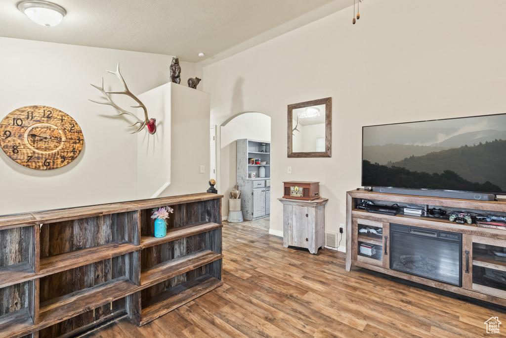 Living area with arched walkways, wood finished floors, and baseboards