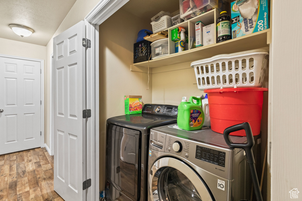 Laundry area with washing machine and dryer and wood finished floors