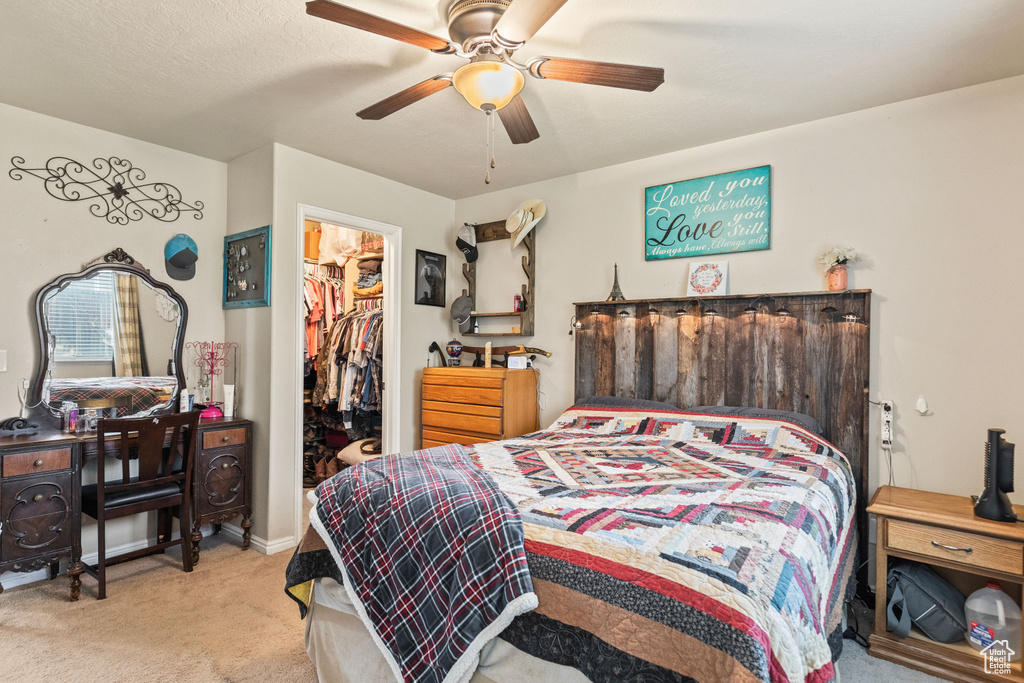 Carpeted bedroom featuring a spacious closet, ceiling fan, and a closet