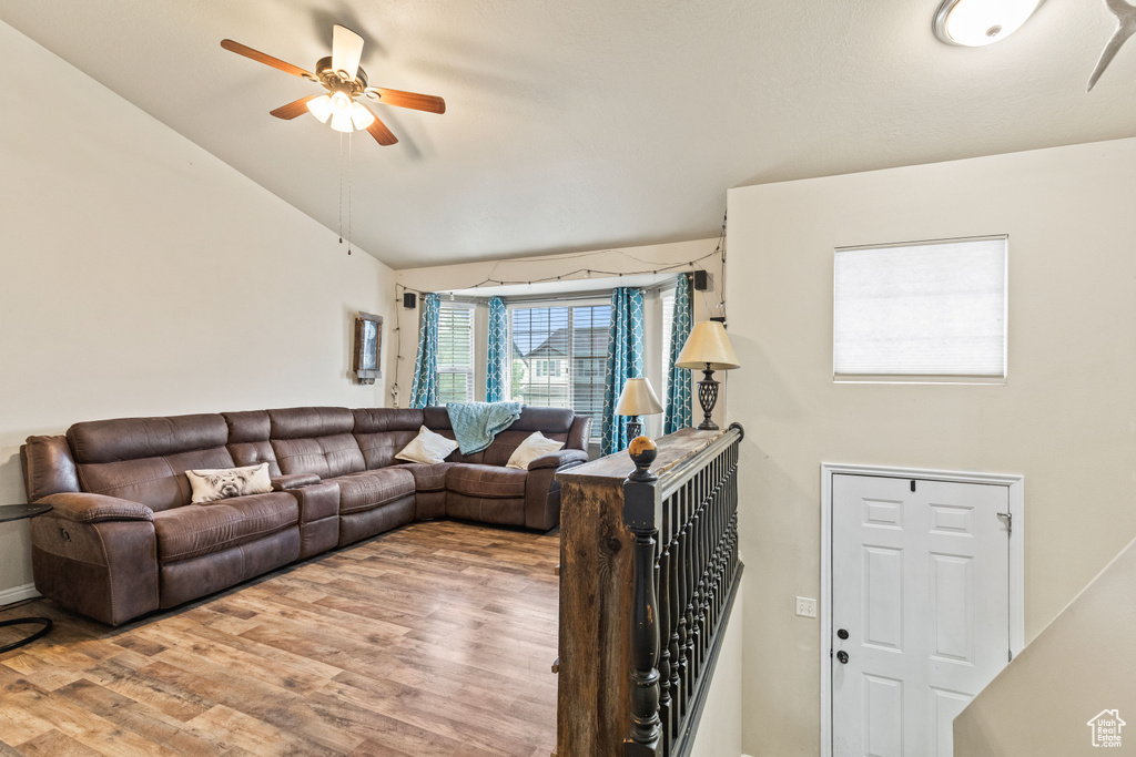 Living area with light wood-style flooring, a ceiling fan, vaulted ceiling, and baseboards