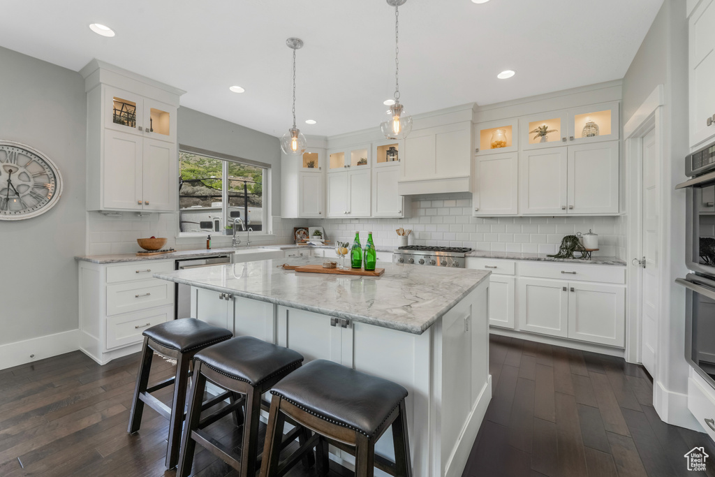 Kitchen with dark wood-style floors, white cabinets, a kitchen island, and recessed lighting