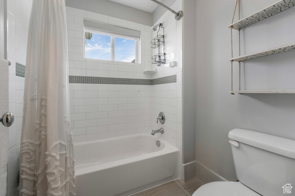 Full bathroom with toilet, baseboards, shower / bathtub combination with curtain, and tile patterned flooring