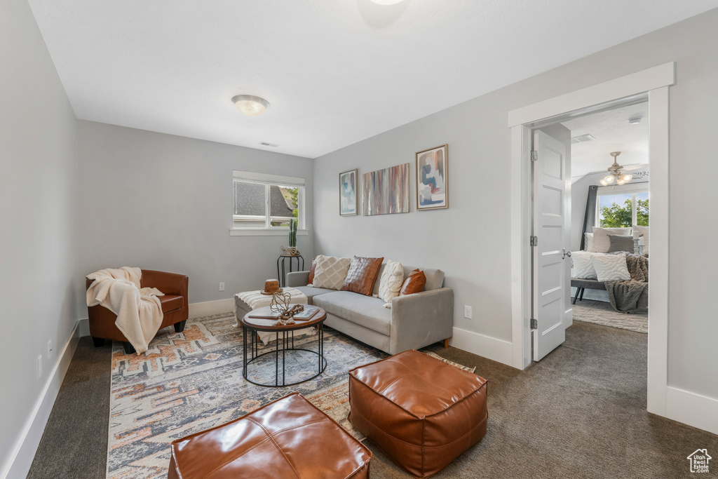 Carpeted living room with healthy amount of natural light, baseboards, and ceiling fan