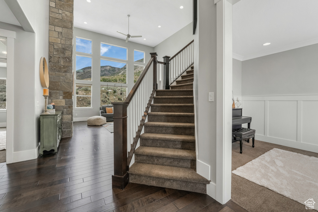 Staircase with a ceiling fan, wood finished floors, a decorative wall, recessed lighting, and a wainscoted wall