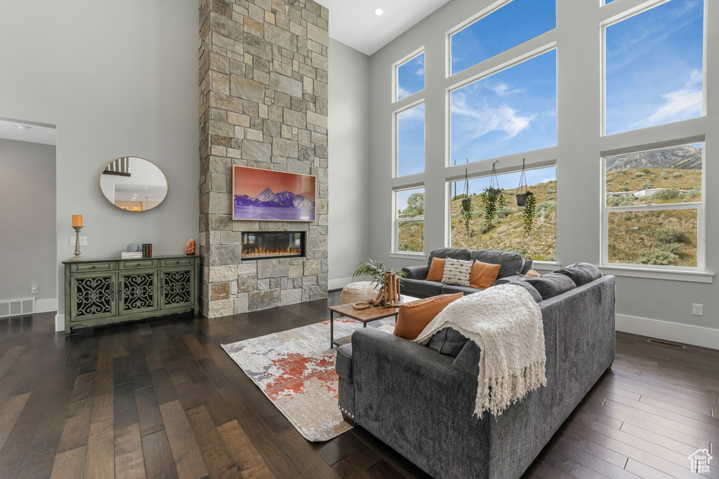 Living room with a towering ceiling, wood-type flooring, a fireplace, and baseboards