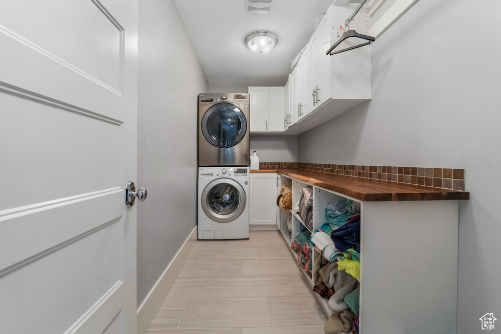 Laundry area with stacked washer / dryer, cabinet space, and baseboards
