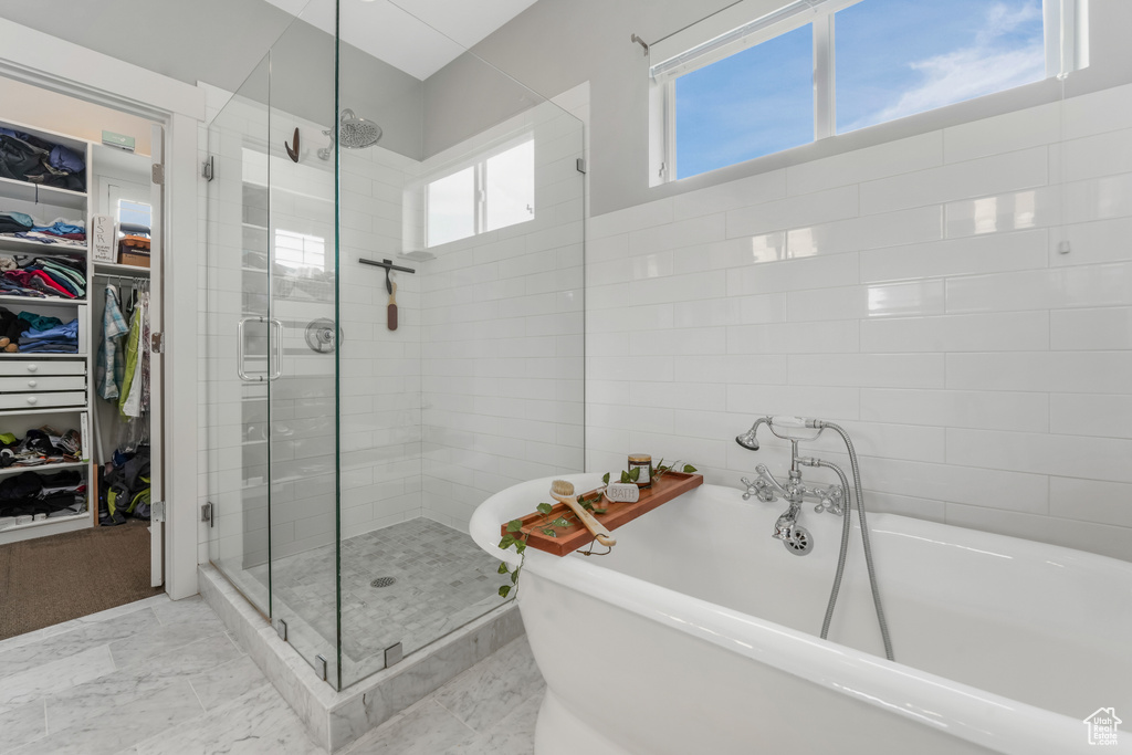 Full bathroom featuring a shower stall, a freestanding tub, and a spacious closet