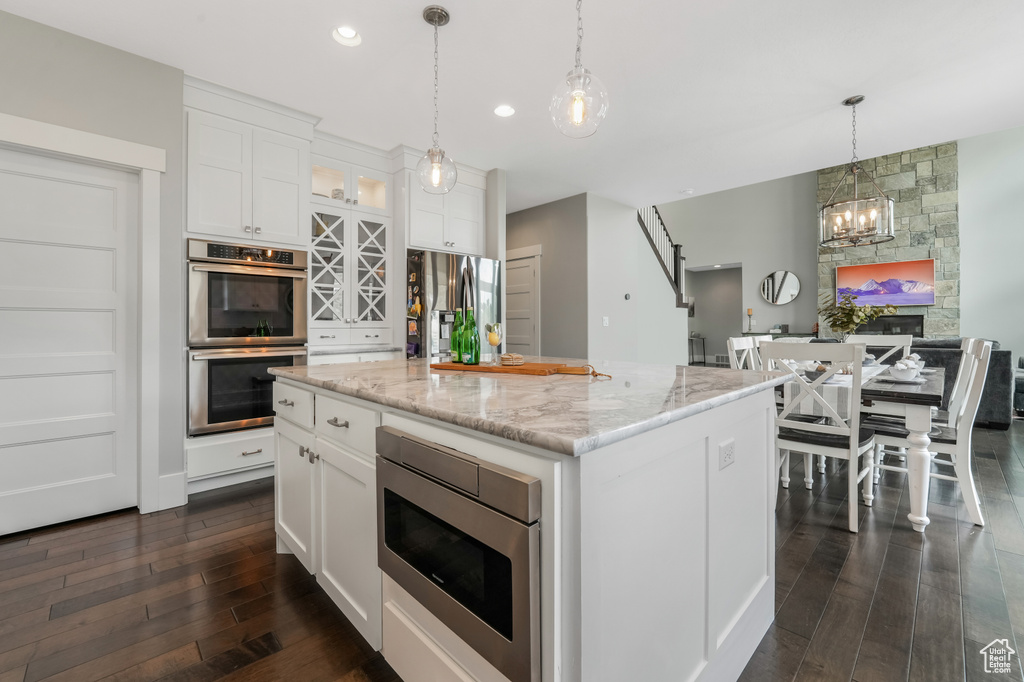 Kitchen featuring appliances with stainless steel finishes, dark wood-style floors, white cabinetry, hanging light fixtures, and recessed lighting