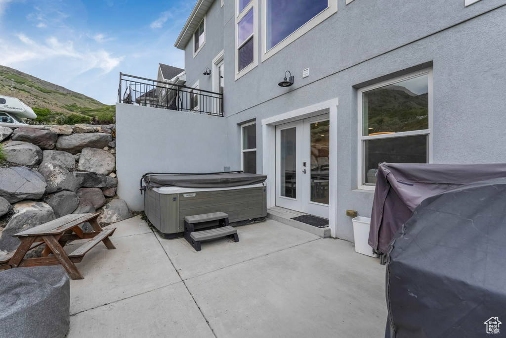 View of patio / terrace with a hot tub, french doors, and a balcony