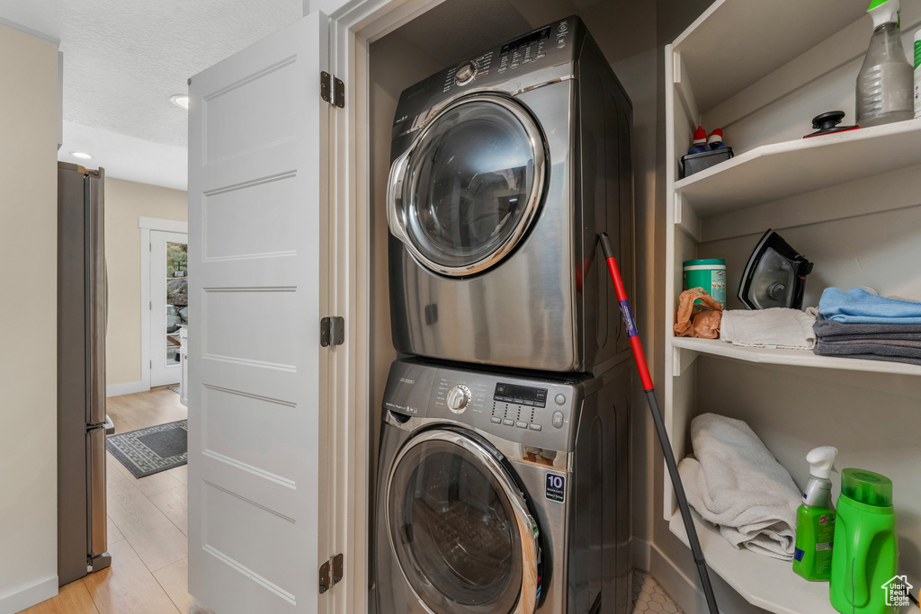 Laundry room featuring stacked washer / drying machine and a textured ceiling