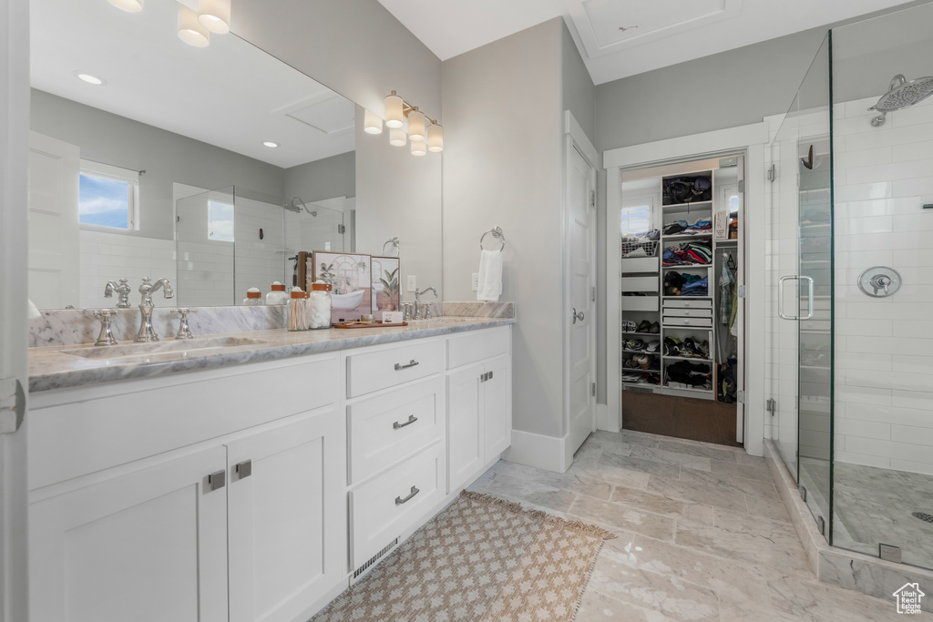 Full bath with a shower stall, double vanity, and a spacious closet