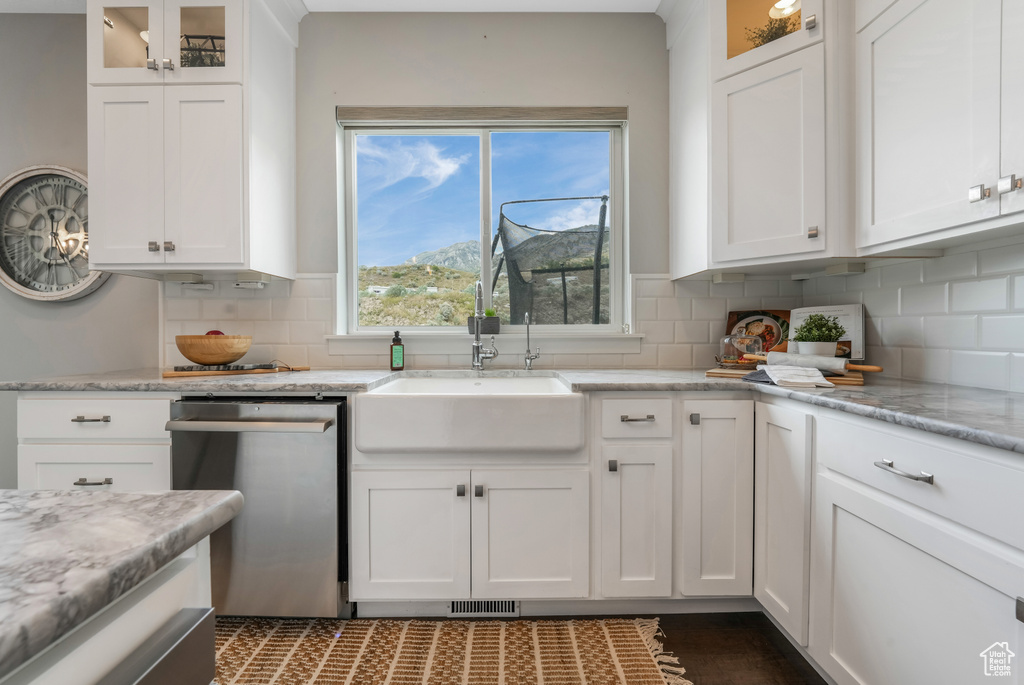 Kitchen with stainless steel dishwasher, a sink, and white cabinets