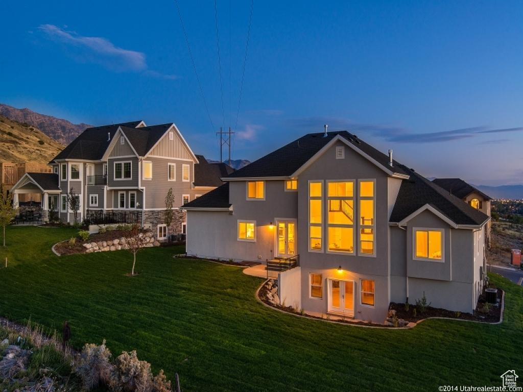 Back of house at dusk with a yard, stucco siding, and a mountain view