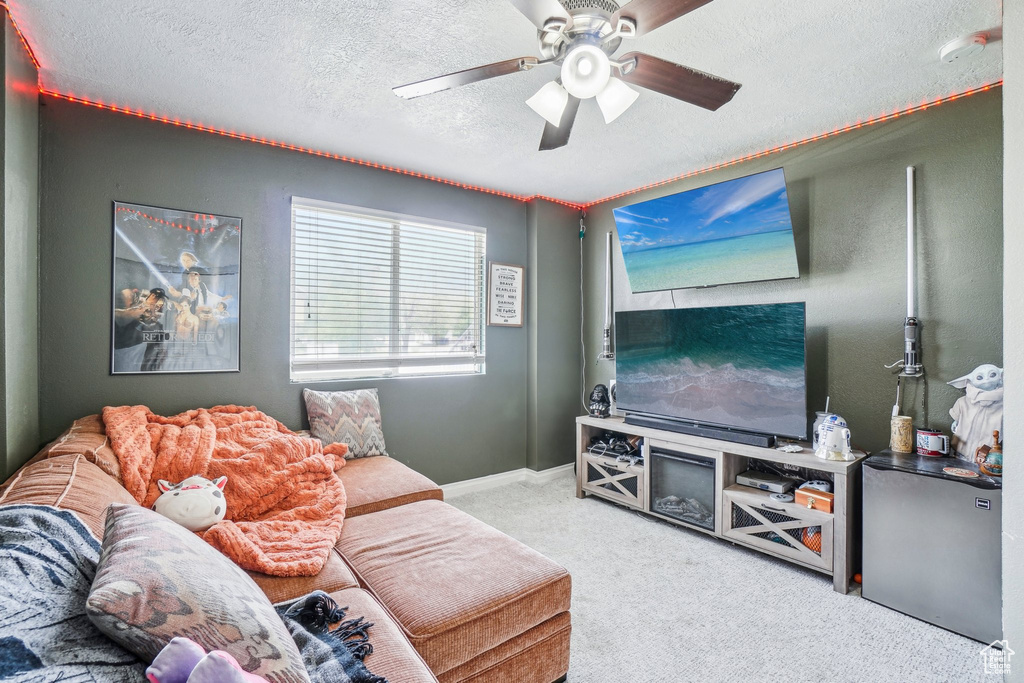 Carpeted living area featuring a textured ceiling and a ceiling fan